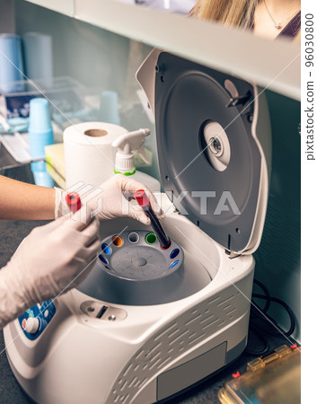 Nurse put blood sample in laboratory centrifuge 96030800