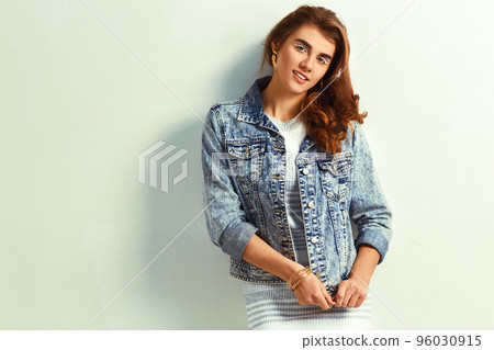 beautiful young blonde woman in nice dress and jeans jacket posing on white background in a studio. 96030915