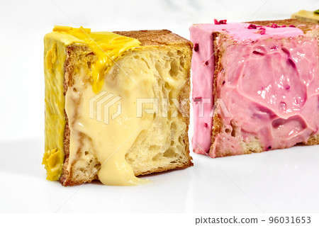 Halves of cube shaped croissants with vanilla custard and berry cream on white background 96031653