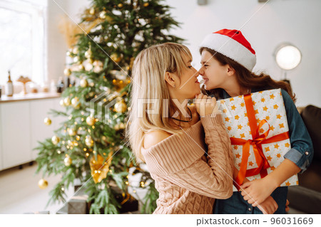 Happy mom and her cute daughter girl exchanging gifts. Merry Christmas and Happy Holidays. 96031669
