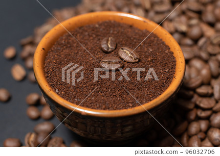 A cup of coffee with beans scattered nearby 96032706