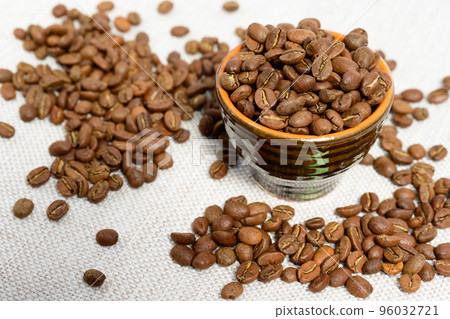 A cup with coffee beans on the background, spilled coffee beans near the cup. 96032721