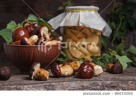 Pile of Imleria Badia or Boletus badius mushrooms commonly known as the bay bolete with canned mushroom in glass jar on vintage wooden background.. Pile of Imleria Badia or Boletus badius mushrooms commonly known as the bay bolete with canned mushroom in glass jar on vintage wooden background.. 96033008