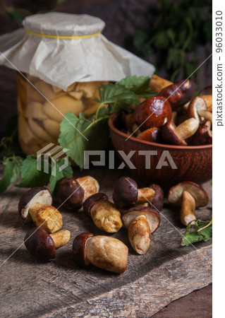 Pile of Imleria Badia or Boletus badius mushrooms commonly known as the bay bolete with canned mushroom in glass jar on vintage wooden background.. Pile of Imleria Badia or Boletus badius mushrooms commonly known as the bay bolete with canned mushroom in glass jar on vintage wooden background.. 96033010