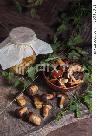Pile of Imleria Badia or Boletus badius mushrooms commonly known as the bay bolete with canned mushroom in glass jar on vintage wooden background.. 96033011