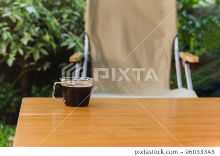Cup of black coffee on wooden table in the garden. Cup of black coffee on wooden table in the garden. 96033348