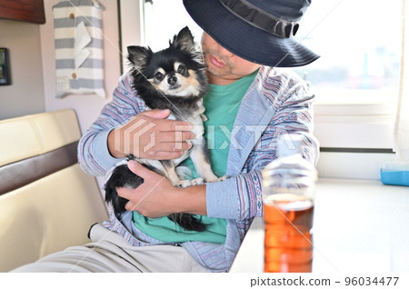 A man relaxing with a chihuahua in a camper A man relaxing with a chihuahua in a camper 96034477