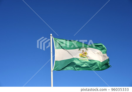 Andalusian flag blowing in the wind with a blue sky in the background Andalusian flag blowing in the wind with a blue sky in the background 96035333
