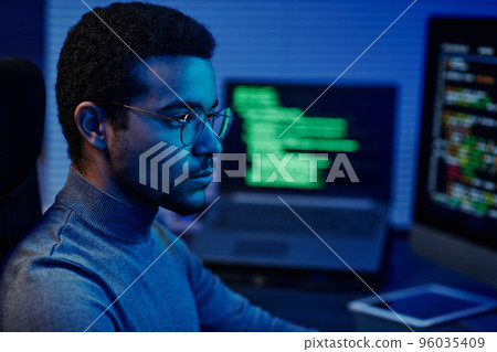 Young serious IT support engineer in eyeglasses looking at computer screen 96035409