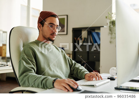 Professional IT engineer in eyeglasses looking at computer screen 96035486