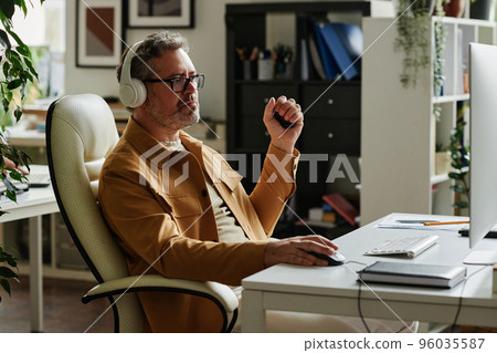 Mature webdesigner squeezing antistress toy while networking 96035587