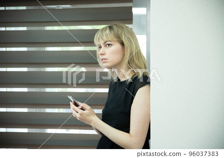一個女人在窗邊看著一部嚴肅的智能手機 96037383