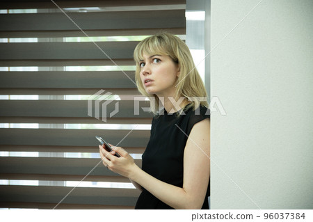 A woman looking at a smartphone with a serious face by the window 96037384