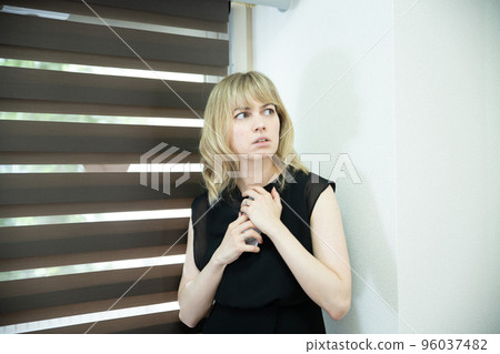 一個女人在窗邊看著一部嚴肅的智能手機 96037482