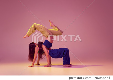 Contemporary dance couple in motion and action isolated on crystal pink background. Young stylish fashionable girls dancing. Art, fashion, style 96038361