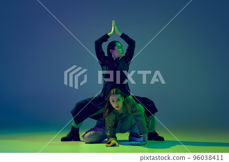 Two dancers, stylish fashionable dance couple dancing contemporary dance on colorful gradient blue-green background in neon light. Concept of art, creativity, movement, style and fashion, action. 96038411