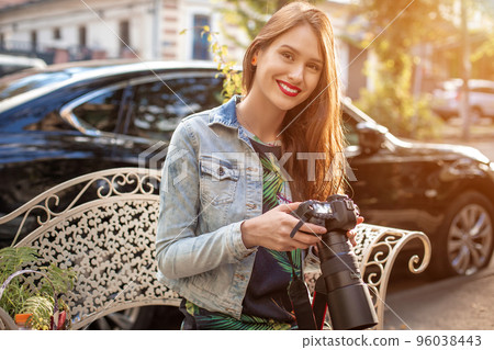 Portrait of professional female photographer on the street photographing on a camera. 96038443