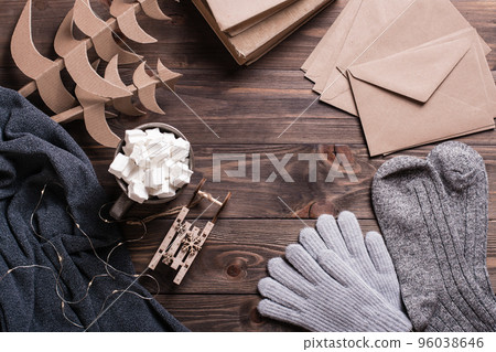 Winter still life. Marshmallow drink, warm clothes, craft envelopes and Christmas trees on a wooden 96038646