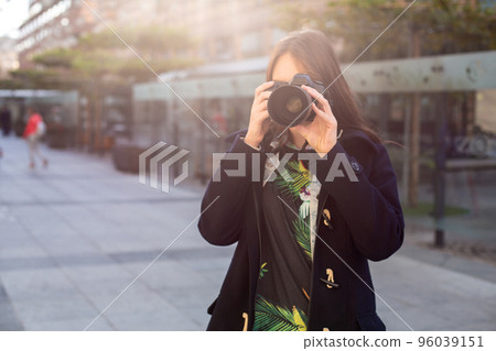 Attractive tourist woman photographer with camera, outdoor in city street. Sun flare 96039151