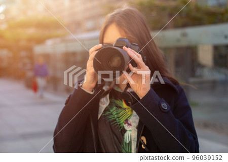 Attractive tourist woman photographer with camera, outdoor in city street. Sun flare 96039152