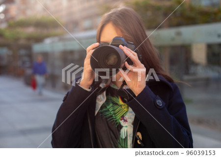Portrait of professional female photographer on the street photographing on a camera. 96039153
