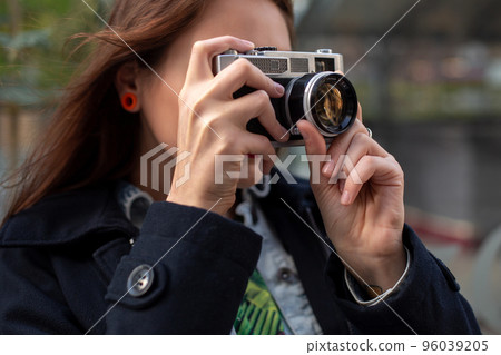 Portrait of a pretty young tourist taking photographs with vintage retro camera 96039205