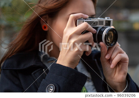 Outdoor autumn smiling lifestyle portrait of pretty young woman, having fun in the city with camera, travel photo of photographer. 96039206