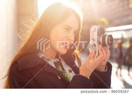 Outdoor autumn smiling lifestyle portrait of pretty young woman, having fun in the city with camera, travel photo of photographer. Outdoor autumn smiling lifestyle portrait of pretty young woman, having fun in the city with camera, travel photo of photographer. 96039267