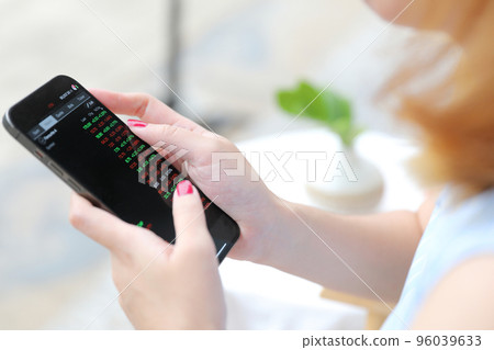 Female hand with smartphone trading stocks online in coffee shop Business concept 96039633