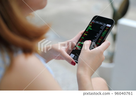 Female hand with smartphone trading stocks online in coffee shop Business concept 96040761
