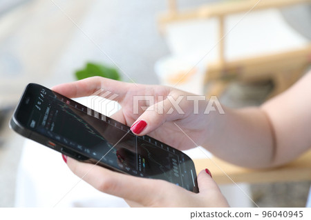 Female hand with smartphone trading stocks online in coffee shop Business concept Female hand with smartphone trading stocks online in coffee shop Business concept 96040945