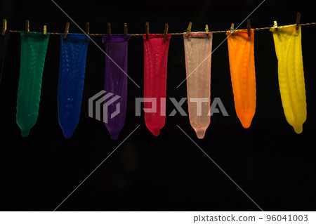 many contraceptives condoms hanging on a rope isolated on black background 96041003