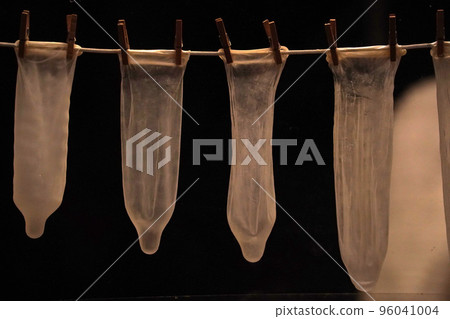 many contraceptives condoms hanging on a rope isolated on black background 96041004