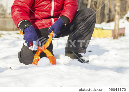 Device for sculpting snowballs in childrens hands on background of snow Device for sculpting snowballs in childrens hands on background of snow 96041170