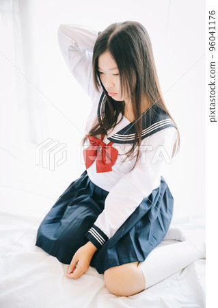 school girl sitting in white tone bed room school girl sitting in white tone bed room 96041176