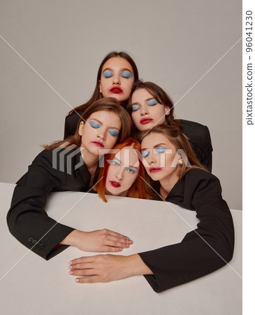 Portrait of young beautiful women in black jackets and red lipstick makeup posing over grey background. 90s look Portrait of young beautiful women in black jackets and red lipstick makeup posing over grey background. 90s look 96041230