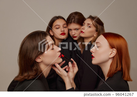 Portrait of young beautiful women in black jackets and red lipstick makeup posing over grey background. Preparation Portrait of young beautiful women in black jackets and red lipstick makeup posing over grey background. Preparation 96041267