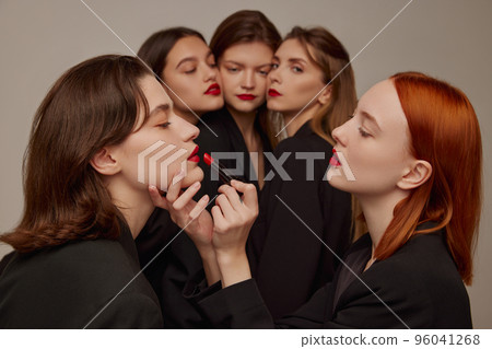 Portrait of young beautiful women in black jackets and red lipstick makeup posing over grey background. Getting ready Portrait of young beautiful women in black jackets and red lipstick makeup posing over grey background. Getting ready 96041268
