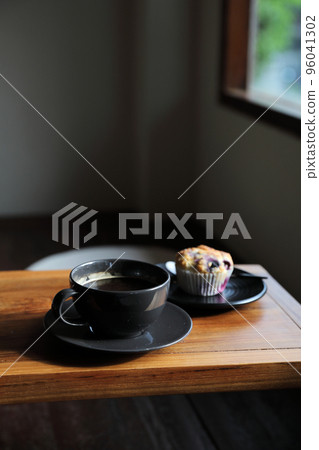 Coffee cup with muffin on wood table in local coffee shop Coffee cup with muffin on wood table in local coffee shop 96041302
