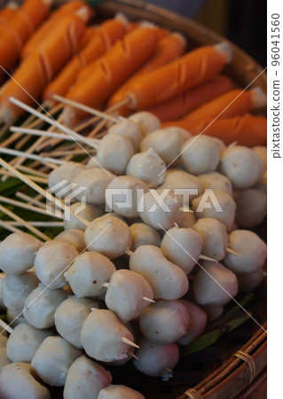 closeup pork meatballs skewers and sausage stacked and green pandan leaf on a bamboo tray 96041560