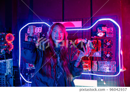 Winning. Young woman feeling excited at gaming room, Happy gamer people playing video game online with smart mobile phone with neon lights raises hands to wins celebrating, smile with smartphone 96042937