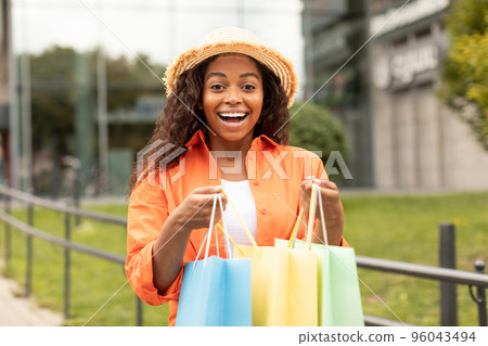 Cheerful shocked emotional pretty millennial black woman in hat opens a lot of packages with purchases, enjoys buy Cheerful shocked emotional pretty millennial black woman in hat opens a lot of packages with purchases, enjoys buy 96043494