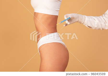 Beauty treatment concept. Cropped view of young fit woman getting injection in belly area, having procedure in salon 96043509