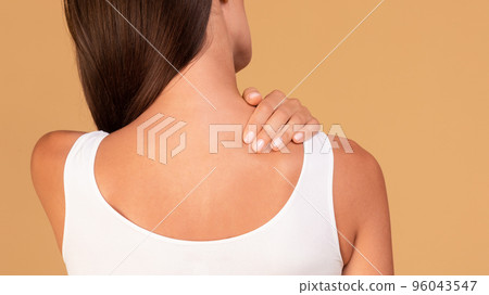 Young caucasian woman suffering from acute pain in her shoulder, touching sore zone and massaging it, panorama Young caucasian woman suffering from acute pain in her shoulder, touching sore zone and massaging it, panorama 96043547