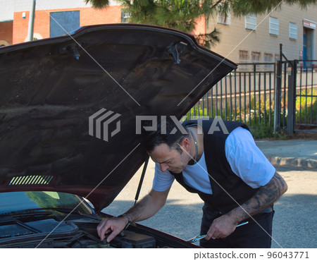 mature man fixing a breakdown in his car engine with tools mature man fixing a breakdown in his car engine with tools 96043771