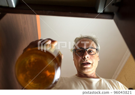 mature man picking up a bottle from the bar cabinet at home 96043821