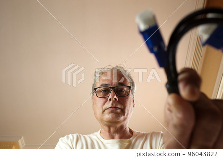 mature man taking a cable from a drawer at home 96043822