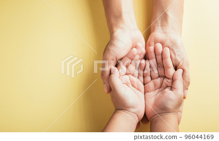 Close up hands children on adult mother hand, Top view person kid stack mom palms, Parents and little kid holding empty hands together isolated on yellow background, Family day care concept 96044169