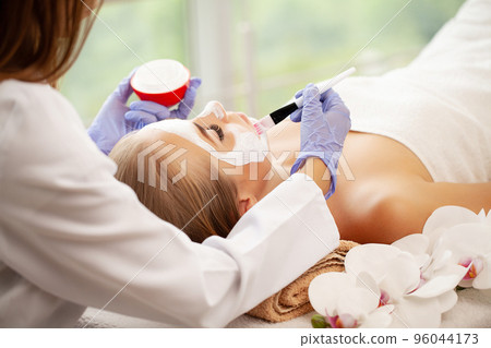 Woman getting facial care by beautician at spa salon 96044173