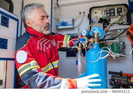Concentrated paramedic preparing the breathing apparatus for oxygen therapy Concentrated paramedic preparing the breathing apparatus for oxygen therapy 96044211